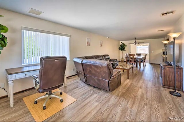 living area with light wood-style floors, visible vents, and baseboards