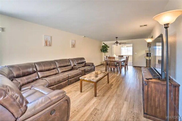 living room featuring a ceiling fan, visible vents, and light wood finished floors