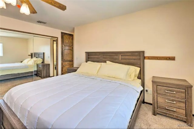 bedroom featuring ceiling fan, visible vents, a closet, and light colored carpet