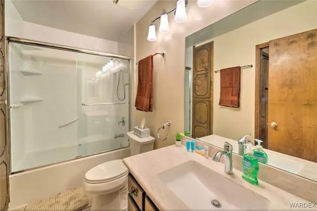 bathroom featuring toilet, enclosed tub / shower combo, and vanity