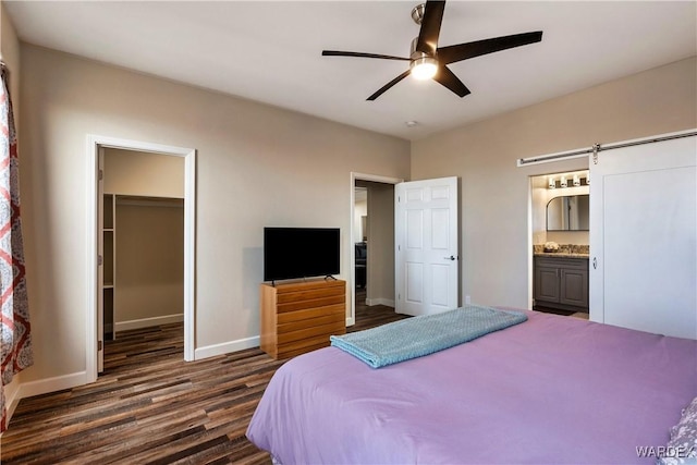 bedroom with connected bathroom, dark wood-style flooring, baseboards, a closet, and a walk in closet