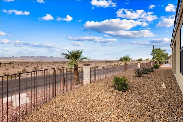 view of yard featuring fence, a mountain view, and a rural view