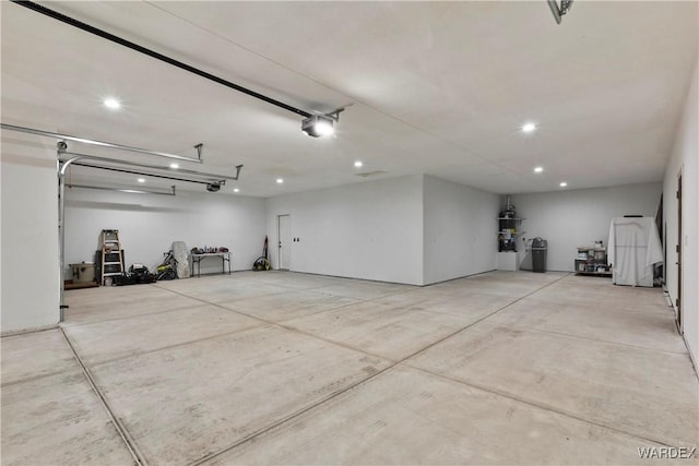 garage with recessed lighting, strapped water heater, and a garage door opener