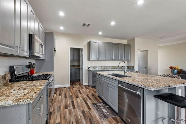 kitchen featuring visible vents, dark wood-type flooring, gray cabinets, stainless steel appliances, and a sink