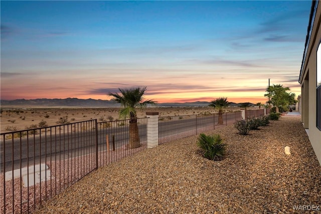 yard at dusk featuring fence and a mountain view