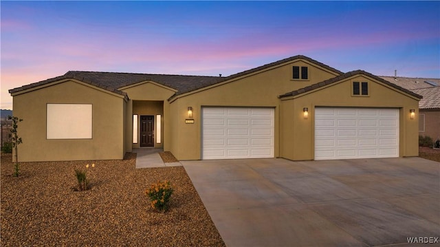 ranch-style house featuring driveway, an attached garage, and stucco siding