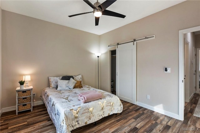 bedroom featuring dark wood-style floors, baseboards, and a barn door