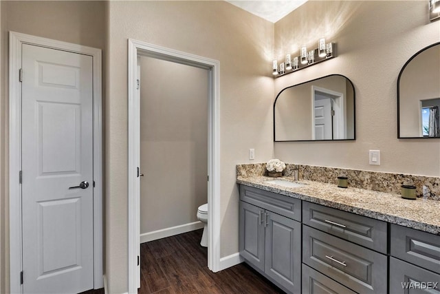 full bathroom with baseboards, toilet, wood finished floors, vanity, and a closet