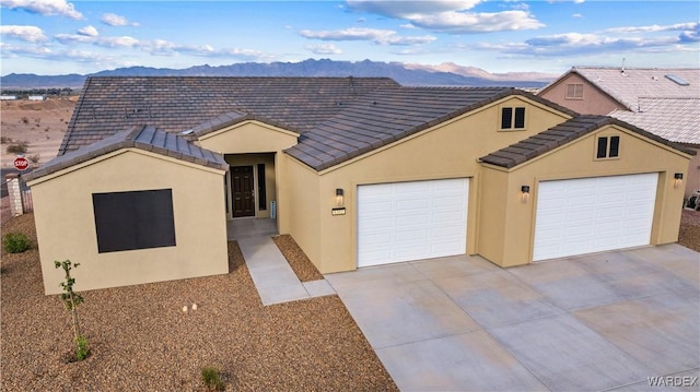 view of front of property featuring an attached garage, a mountain view, concrete driveway, and a tiled roof