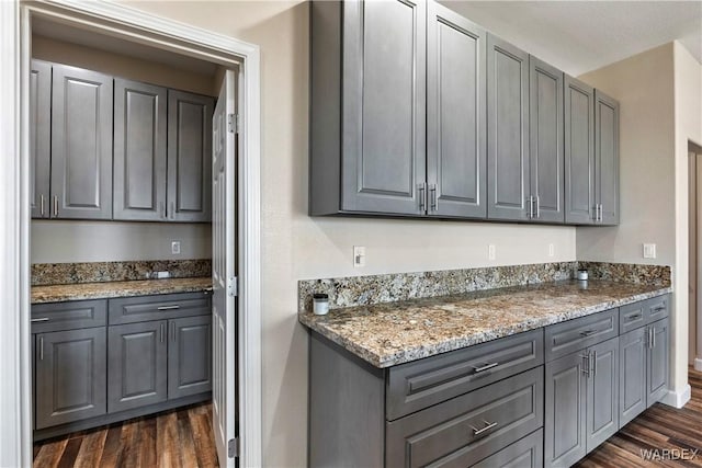 kitchen featuring dark stone counters, gray cabinets, and dark wood finished floors