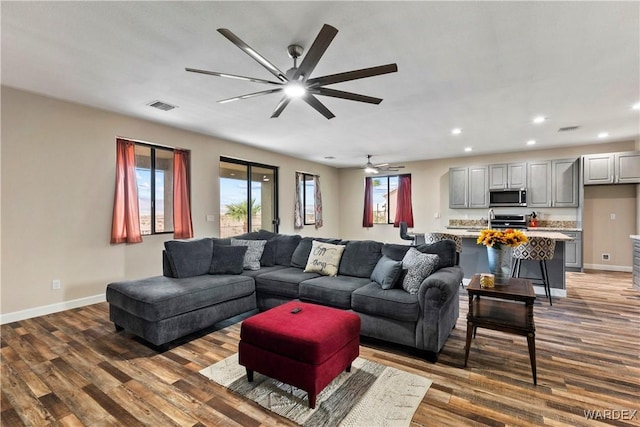 living area with recessed lighting, visible vents, dark wood finished floors, and baseboards