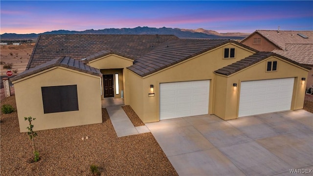 view of front of property featuring a garage, a tile roof, driveway, and stucco siding