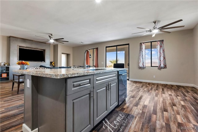 kitchen with open floor plan, light countertops, a center island with sink, and a sink