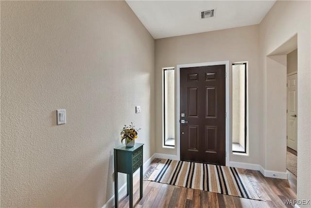 entrance foyer featuring baseboards, visible vents, and dark wood-style flooring