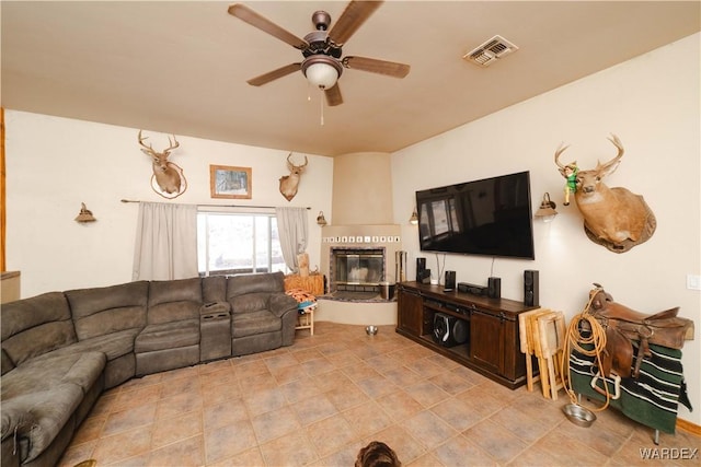 living area featuring ceiling fan, visible vents, and a glass covered fireplace