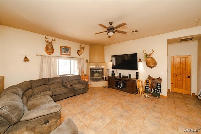 living room featuring ceiling fan, a glass covered fireplace, and visible vents