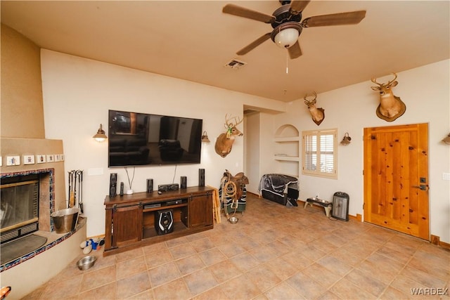 living room featuring a ceiling fan, a glass covered fireplace, and visible vents