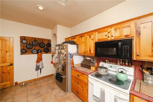 kitchen with baseboards, tile counters, electric stove, stainless steel fridge with ice dispenser, and black microwave