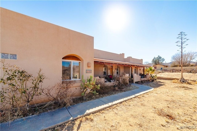 rear view of property with a tile roof and stucco siding