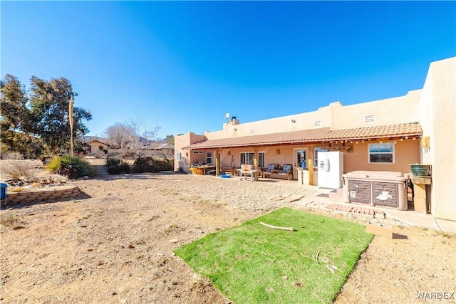 rear view of property with stucco siding, a tile roof, an outdoor kitchen, and a patio