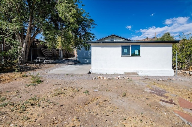 view of side of property featuring a patio area, fence, and stucco siding