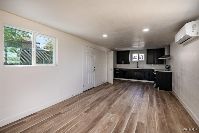 kitchen featuring dark cabinets, light countertops, electric stove, wall chimney exhaust hood, and a wall mounted air conditioner