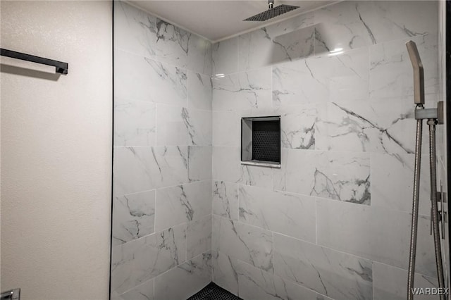 full bath featuring a tile shower and a textured wall