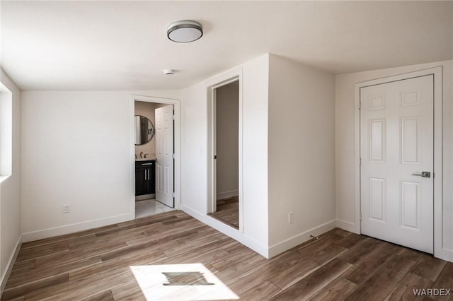 interior space featuring ensuite bath, wood finished floors, and baseboards