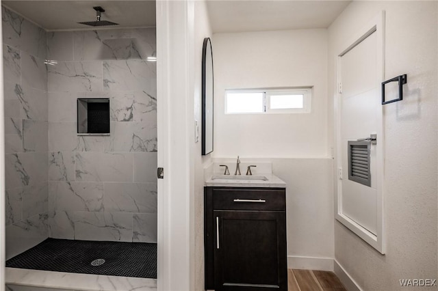 bathroom with a marble finish shower, baseboards, wood finished floors, and vanity