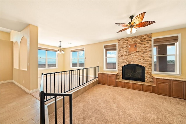 9076 E Mountain Shadow Rd, Kingman, AZ 86401 - unfurnished living room with a ceiling fan, a chandelier, baseboards, a stone fireplace, and light wood-style flooring