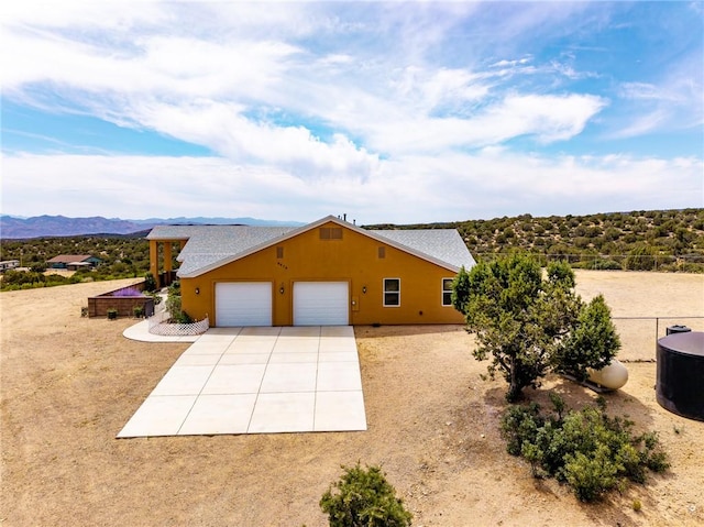 9076 E Mountain Shadow Rd, Kingman, AZ 86401 - view of side of property featuring driveway, an attached garage, a mountain view, roof with shingles, and stucco siding