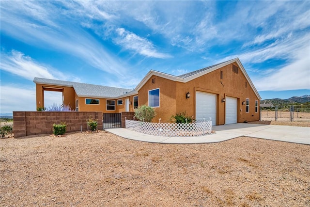 9076 E Mountain Shadow Rd, Kingman, AZ 86401 - ranch-style home featuring an attached garage, driveway, stucco siding, and a fenced front yard
