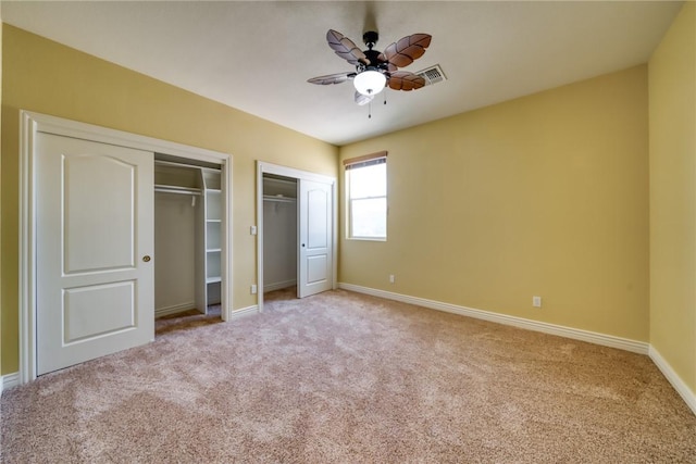 9076 E Mountain Shadow Rd, Kingman, AZ 86401 - unfurnished bedroom featuring multiple closets, light carpet, baseboards, and ceiling fan