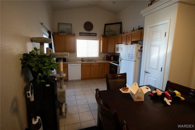 kitchen featuring light tile patterned floors, white appliances, a sink, vaulted ceiling, and light countertops