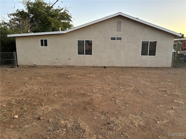 rear view of house featuring stucco siding and fence