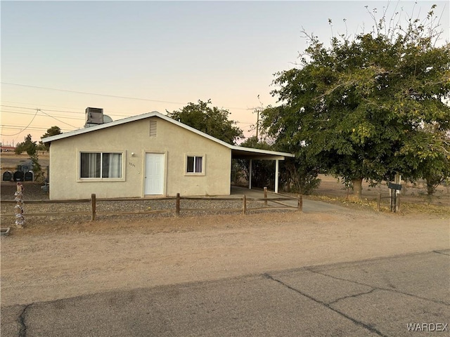 view of front of house with cooling unit, fence, driveway, stucco siding, and a carport