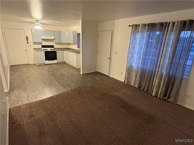 kitchen with ceiling fan, under cabinet range hood, stove, white cabinets, and dark colored carpet