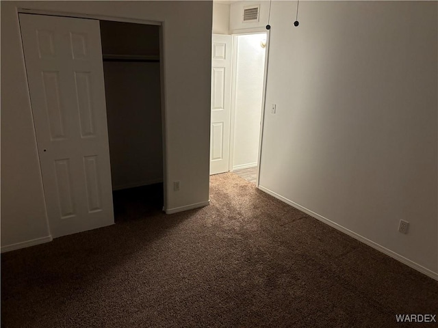 unfurnished bedroom with baseboards, visible vents, and dark carpet