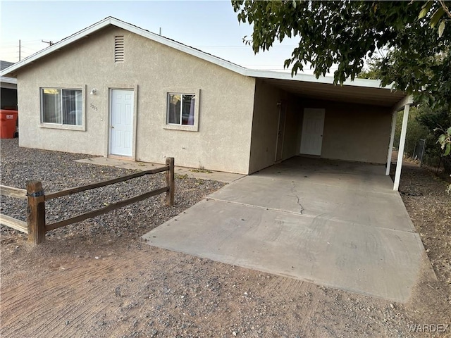 ranch-style house with a carport, stucco siding, driveway, and fence