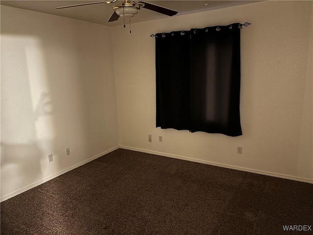 spare room featuring baseboards, ceiling fan, and dark carpet