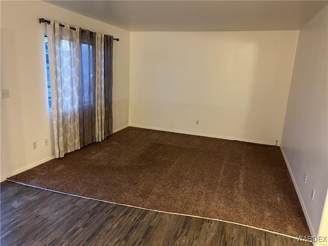 unfurnished room featuring baseboards and wood finished floors