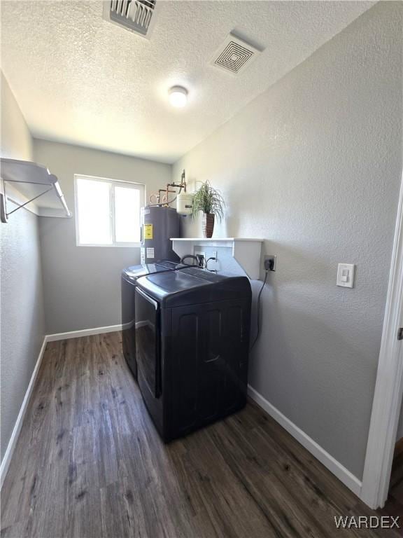 laundry area with visible vents, dark wood-type flooring, electric water heater, separate washer and dryer, and laundry area