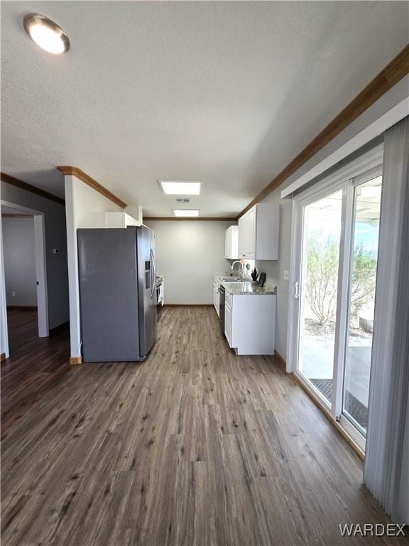 kitchen featuring dark wood-style flooring, crown molding, white cabinetry, a sink, and stainless steel fridge with ice dispenser