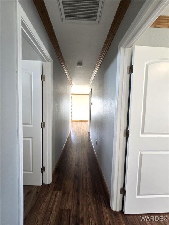 corridor with baseboards, visible vents, dark wood-style flooring, and crown molding