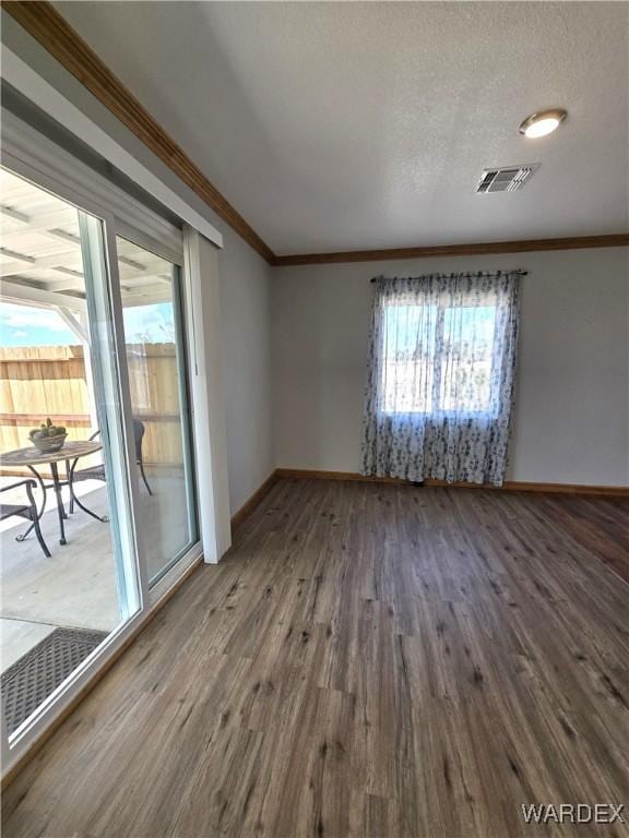 unfurnished room featuring ornamental molding, visible vents, baseboards, and wood finished floors