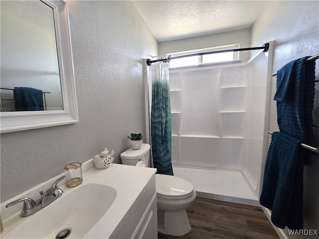 full bathroom with a textured ceiling, a textured wall, and wood finished floors