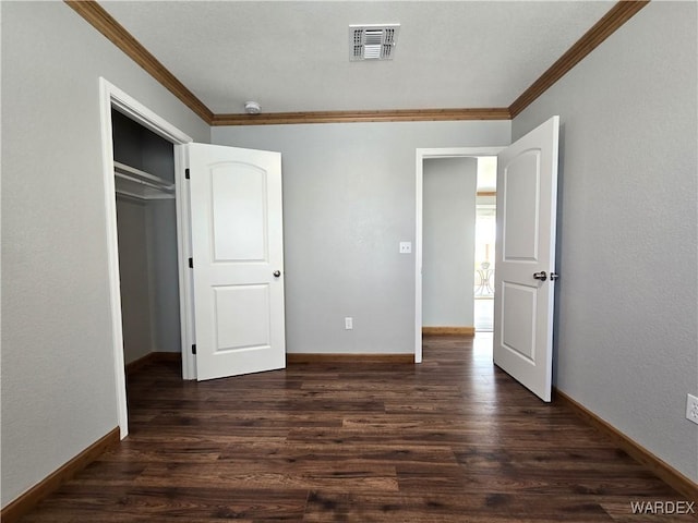 unfurnished bedroom featuring a closet, visible vents, dark wood-type flooring, ornamental molding, and baseboards