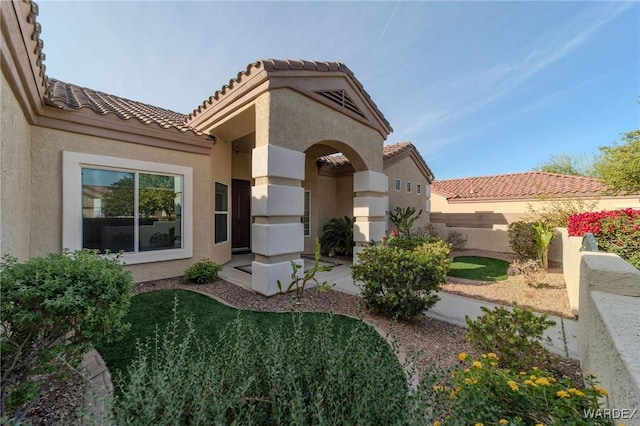 exterior space with a lawn, fence, a tiled roof, and stucco siding