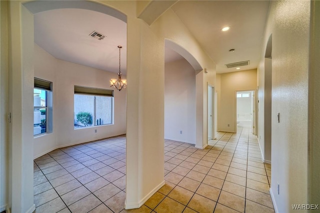 corridor featuring visible vents, a notable chandelier, and light tile patterned flooring