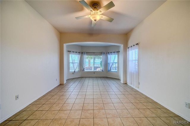 unfurnished room featuring ceiling fan, light tile patterned flooring, and baseboards